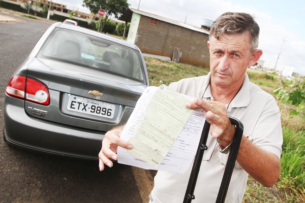 O pastor Alair Venceslau Silva mostra a multa no valor de R$ 85,13 por usar moldura na placa de seu veículo